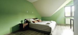 a green bedroom with a bed and a window at Gościniec Na Stoku pokoje 2,3,4 osobowe, cisza, spokój, widok na stok narciarski, lasy, łaki in Bobliwo