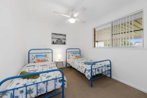 two twin beds in a room with a window at Gone Coastal - pool, river, beach getaway in North Haven +16 photos