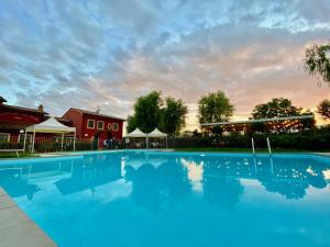 een groot blauw zwembad met een rood gebouw op de achtergrond bij Room in Holiday house - Apartment in Farmhouse Casolare dei Fiori in Chiesina Uzzanese