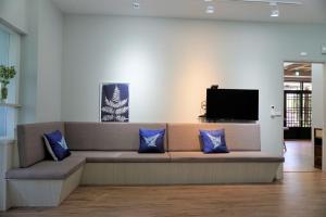 un sofá con almohadas azules en una habitación con TV en 藴慢築 茶花藝主題民宿 Yun Man Zhu Homestay, en Gongguan