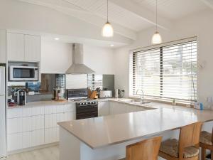 a kitchen with white cabinets and a large white counter top at Kianga Parade Beach House in Kianga