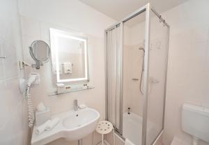 a white bathroom with a sink and a shower at City-Hotel Am Wasserturm Halle in Halle an der Saale