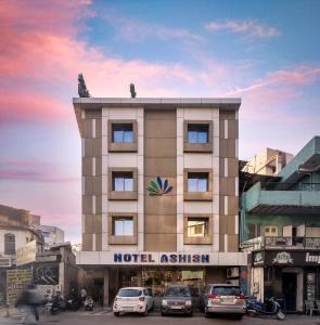 a hotel with cars parked in front of a building at Hotel Ashish in Ahmedabad