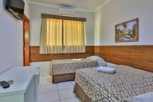 a hotel room with two beds and a window at Hotel Romaria Aparecida in Aparecida