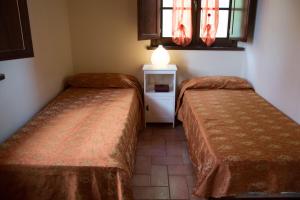 Cette chambre comprend deux lits et une table avec une lampe. dans l'établissement Room in Holiday house - Apartment in Farmhouse, à Montecarlo
