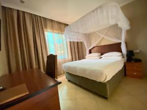 1 dormitorio con cama con dosel y mesa en Sangana Lodge, en Moshi