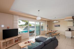 a living room with a couch and a tv and a table at Olive Tree Villas Afandou in Afantou