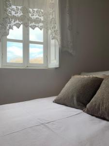 a bedroom with a white bed and a window at Lava House in Mandrákion