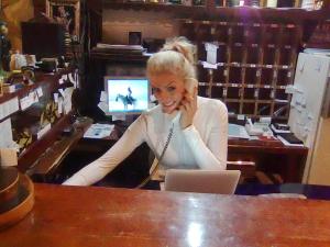 Una mujer sentada en un escritorio hablando por celular en Amfora Rooms Caribrod, en Dimitrovgrad