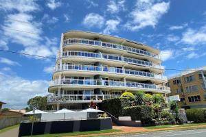 a tall apartment building with balconies and bushes at Belvedere Apartments in Caloundra