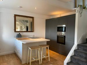 a kitchen with black cabinets and a counter with stools at The Old Dairy in Oughtibridge