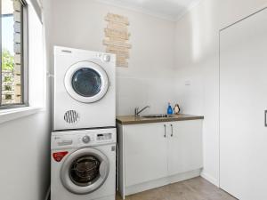 een wasruimte met een wasmachine en een gootsteen bij Maybloom in Rye +11 foto's