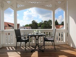 eine abgeschirmte Veranda mit einem Tisch und 2 Stühlen in der Unterkunft Strandvillen Binz - Ferienwohnung mit Meerblick, 2 Schlafzimmern und Balkon SV-761 in Binz