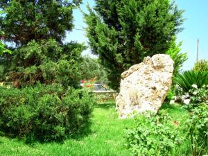 a rock in a garden with bushes and trees at Remenata in Lixouri