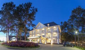 a white building with a car parked in front of it at Rung La Kim Resort in Da Lat