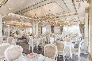 une salle à manger avec des tables, des chaises et des lustres blancs dans l'établissement Hotel & SPA Diamant Residence - All Inclusive, à Sunny Beach