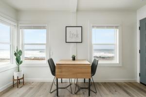 uma sala de jantar com paredes e janelas brancas e uma mesa e cadeiras em The Marbella em Oceanside