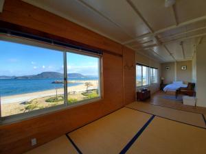 高松市にあるMegijima Beach Apartmentのベッドルーム1室(ビーチの景色を望む大きな窓付)
