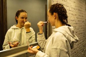 a woman brushing her teeth in front of a mirror at Hostels Rus - Bagration in Moscow