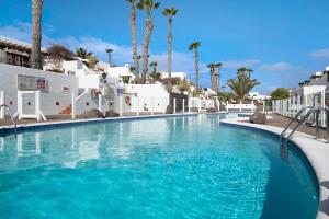 a swimming pool at a resort with palm trees at Puerto Chico P in Playa Blanca