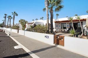 a house with a white fence and palm trees at Puerto Chico P in Playa Blanca