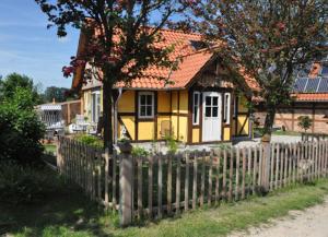 una casa amarilla con una valla delante de ella en Am Sund Hus, en Ulsnis
