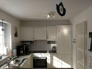 a kitchen with white cabinets and a sink at Fanö Huset in Boren