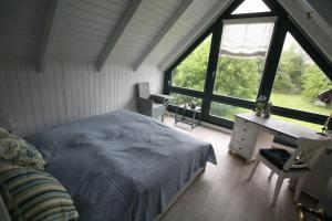 a bedroom with a bed and a desk and windows at Schlei-Juwel in Brodersby
