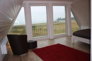 Schlafzimmer mit großen Fenstern, einem Bett und einem roten Teppich in der Unterkunft Weitblick in Brodersby