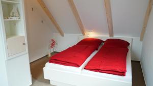 a white bed with red pillows in a room at Utspann in Brodersby
