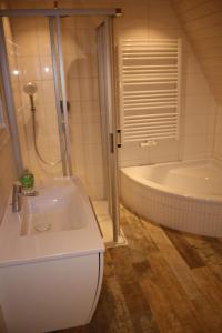 ein Badezimmer mit einem weißen Waschbecken und einer Badewanne in der Unterkunft Weitblick in Brodersby