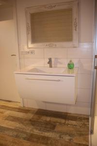 ein Badezimmer mit weißem Waschbecken und Fenster in der Unterkunft Weitblick in Brodersby + 23 Fotos