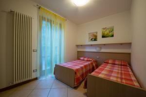 a bedroom with two beds and a large window at ApartmentsGarda - Canevini Residence in Torri del Benaco