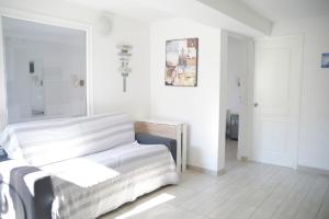 Cette chambre blanche comprend un lit et un miroir. dans l'établissement Sunny apartment in heart of Nice Old Town, à Nice