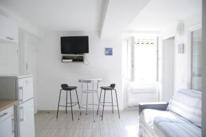 a white living room with a couch and stools at Sunny apartment in heart of Nice Old Town in Nice