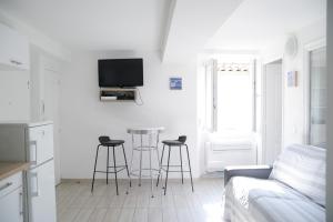 a white living room with a couch and stools at Sunny apartment in heart of Nice Old Town in Nice