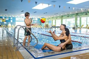 a woman and a man playing with a ball in a swimming pool at Apartment Luna in Ptuj