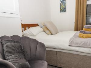 1 dormitorio con 1 cama con silla y sofá en Lemongrass, en Skipton