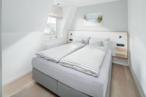 a white bedroom with a bed with a white headboard at Urlaubs-Residenz Norderney in Norderney