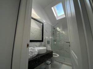 a white bathroom with a sink and a mirror at Erbario House in Bucharest