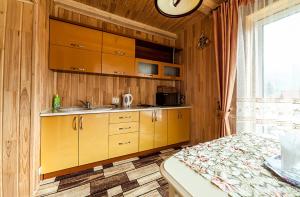 uma cozinha com armários de madeira, um lavatório e uma cama em Olga Hotel SPA em Tatariv