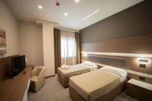 una camera d'albergo con due letti e una televisione di Building Hotel a Teverola