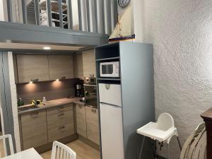 a small kitchen with a refrigerator and a microwave at Collioure, bel appartement de 40m2 avec balcon et parking in Collioure