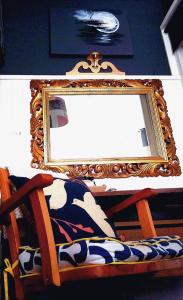 um espelho sentado em cima de uma cadeira de madeira com uma almofada em AVONNOVA INTERIORS em Londres