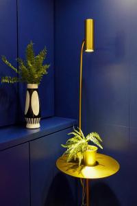 a table with a lamp and plants on a blue wall at Talmud Hotel Gongyuan in Taichung