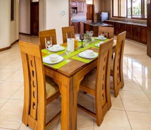 a wooden table with chairs and plates and wine glasses at Luxury 3BR Nyali Beachfront Apartment - 3 Min Walk in Mombasa