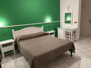 Dormitorio verde con cama y pared verde en Hotel Caribe, en Casalnuovo di Napoli