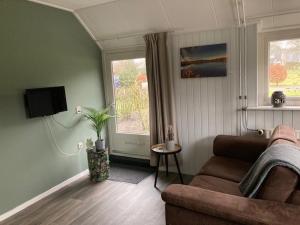 a living room with a couch and a window at De Deelderij in Schoonloo +30 photos