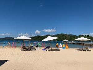 a beach with chairs and umbrellas and the ocean at Pangulatan Beach Resort in El Nido