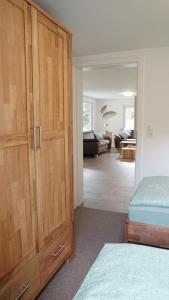 a bedroom with a large wooden cabinet and a living room at Die Fünf in Brodersby